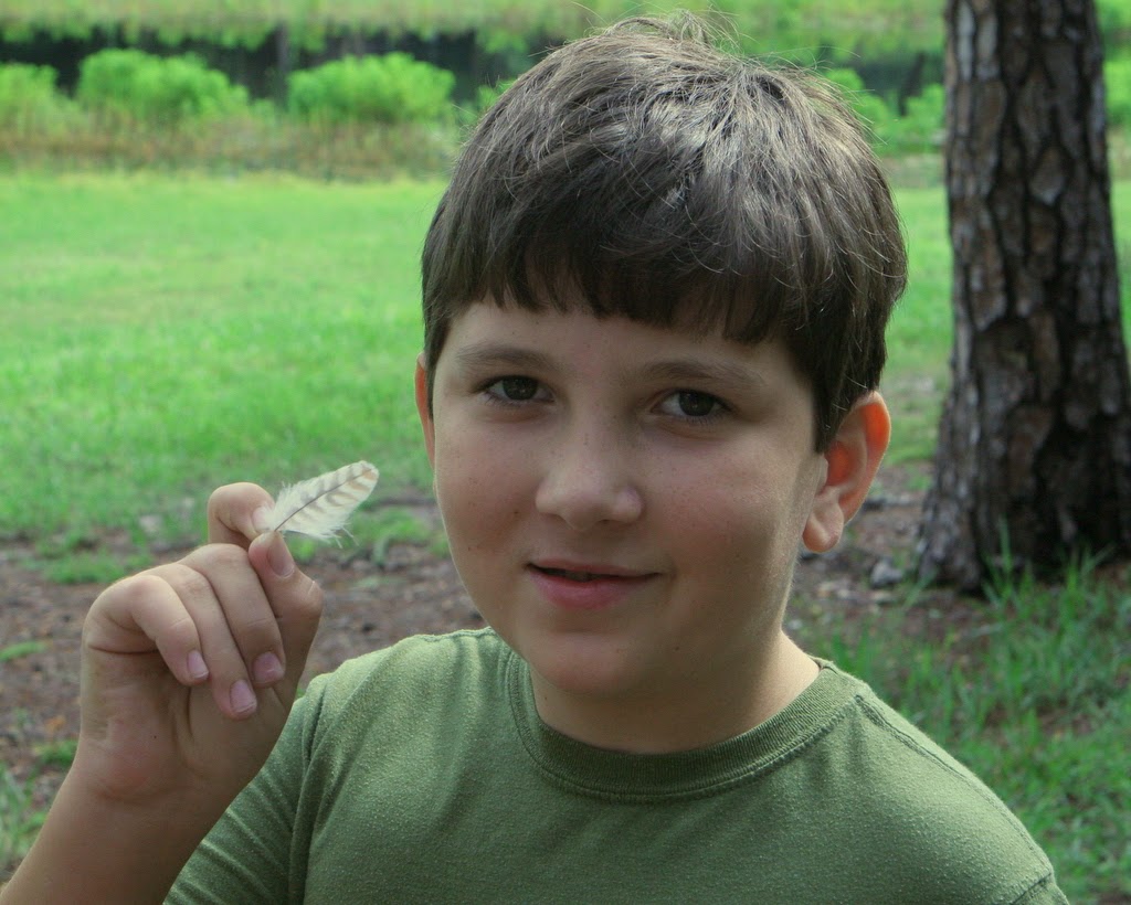 grayson finds a feather on a nature walk